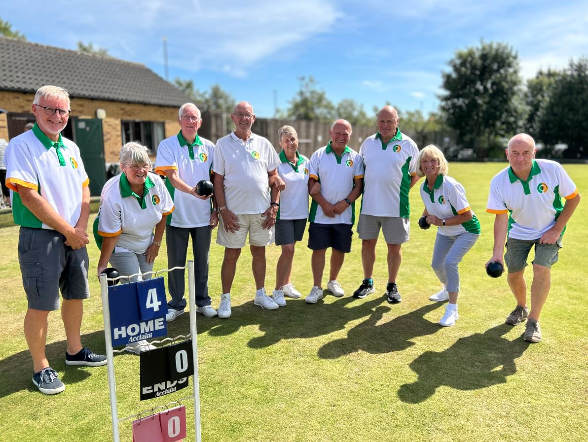 Members of the bowls club on the bowling green with the score board